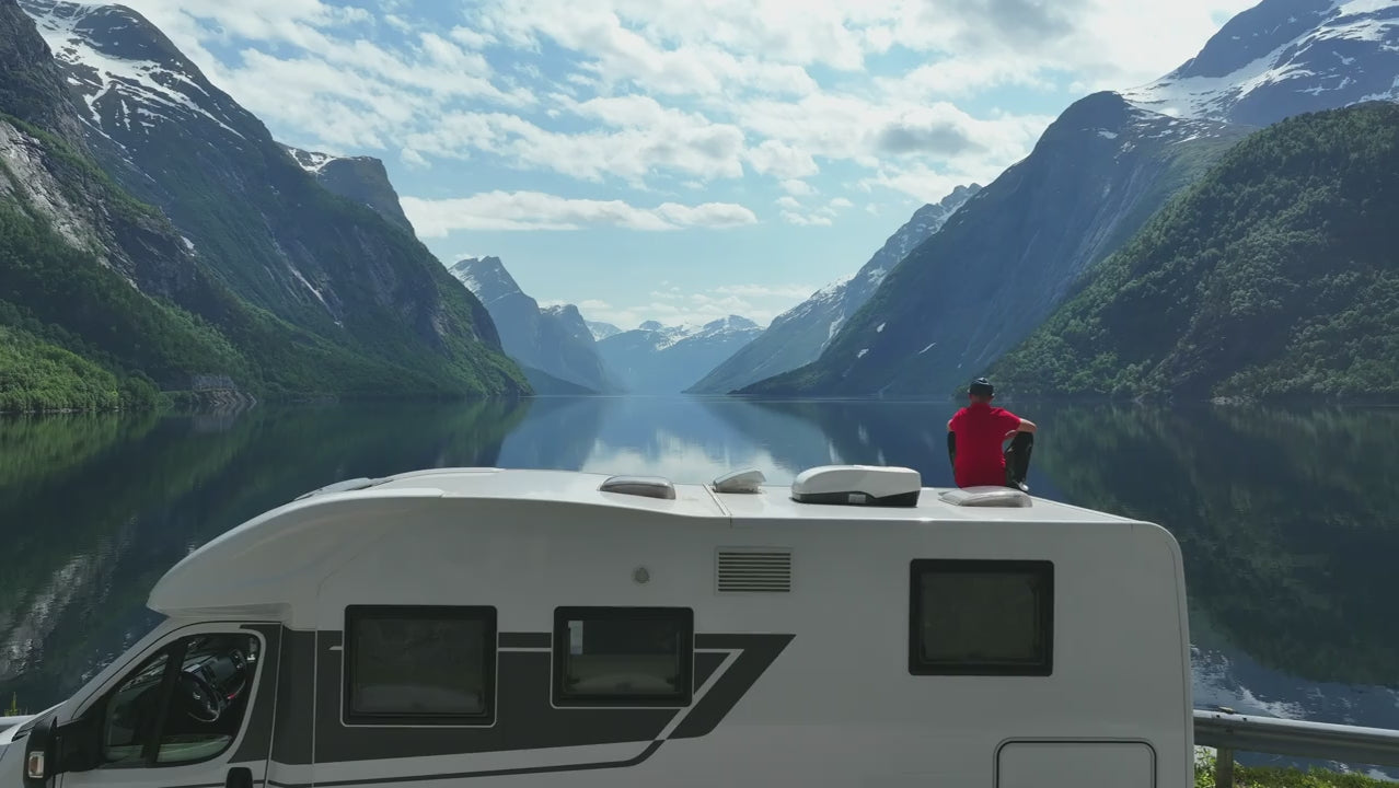 man in the roof of his RV overlooking a lake
